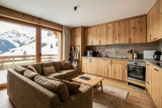Salon d'un appartement à vendre aux Menuires avec vue sur les pistes enneigées et décoration chalet moderne