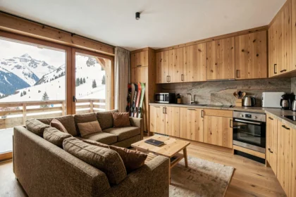 Salon d'un appartement à vendre aux Menuires avec vue sur les pistes enneigées et décoration chalet moderne